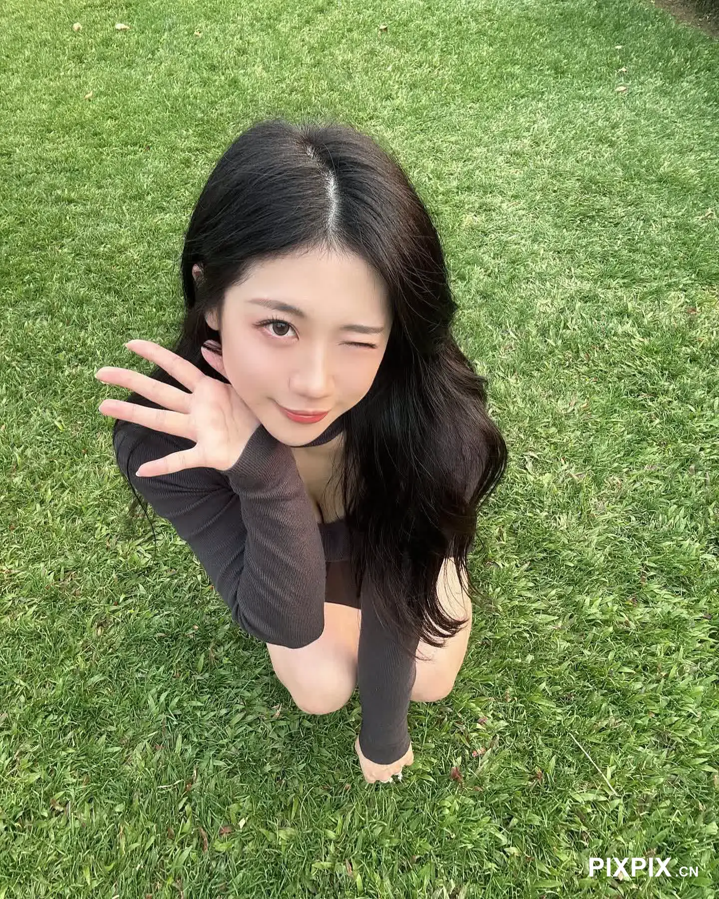 亚洲女人坐在草地上，双手捂脸