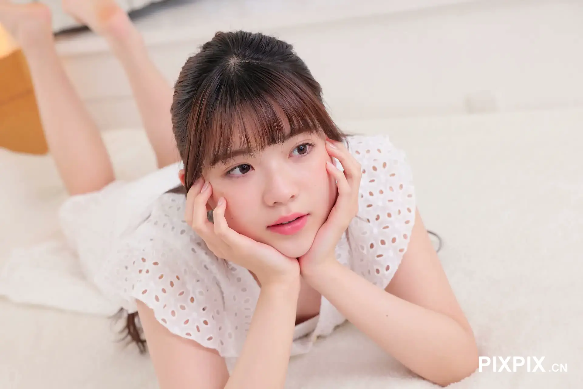 亚洲女孩躺在地板上，双手捂着脸