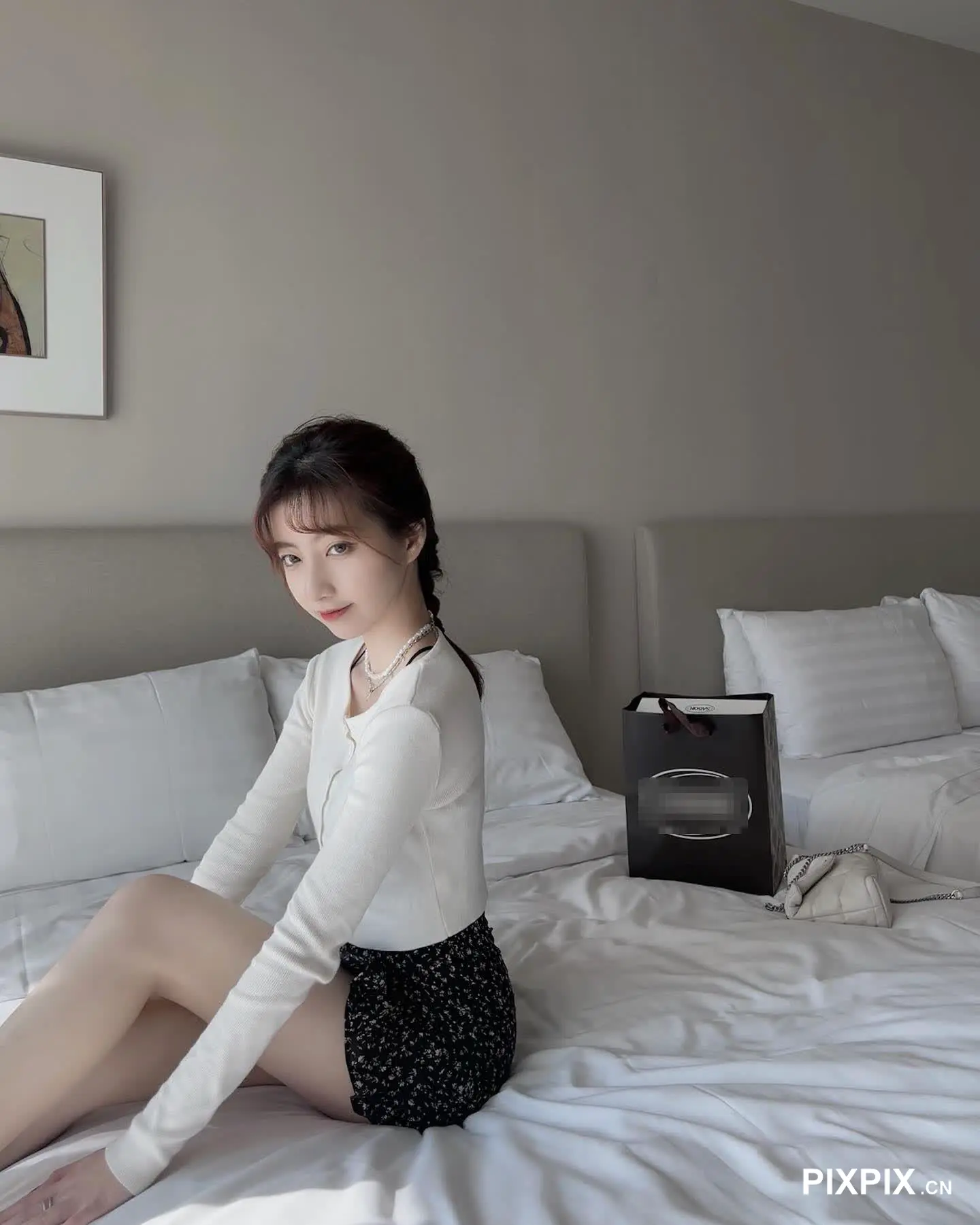 床上坐着一个穿着白衬衫的女人