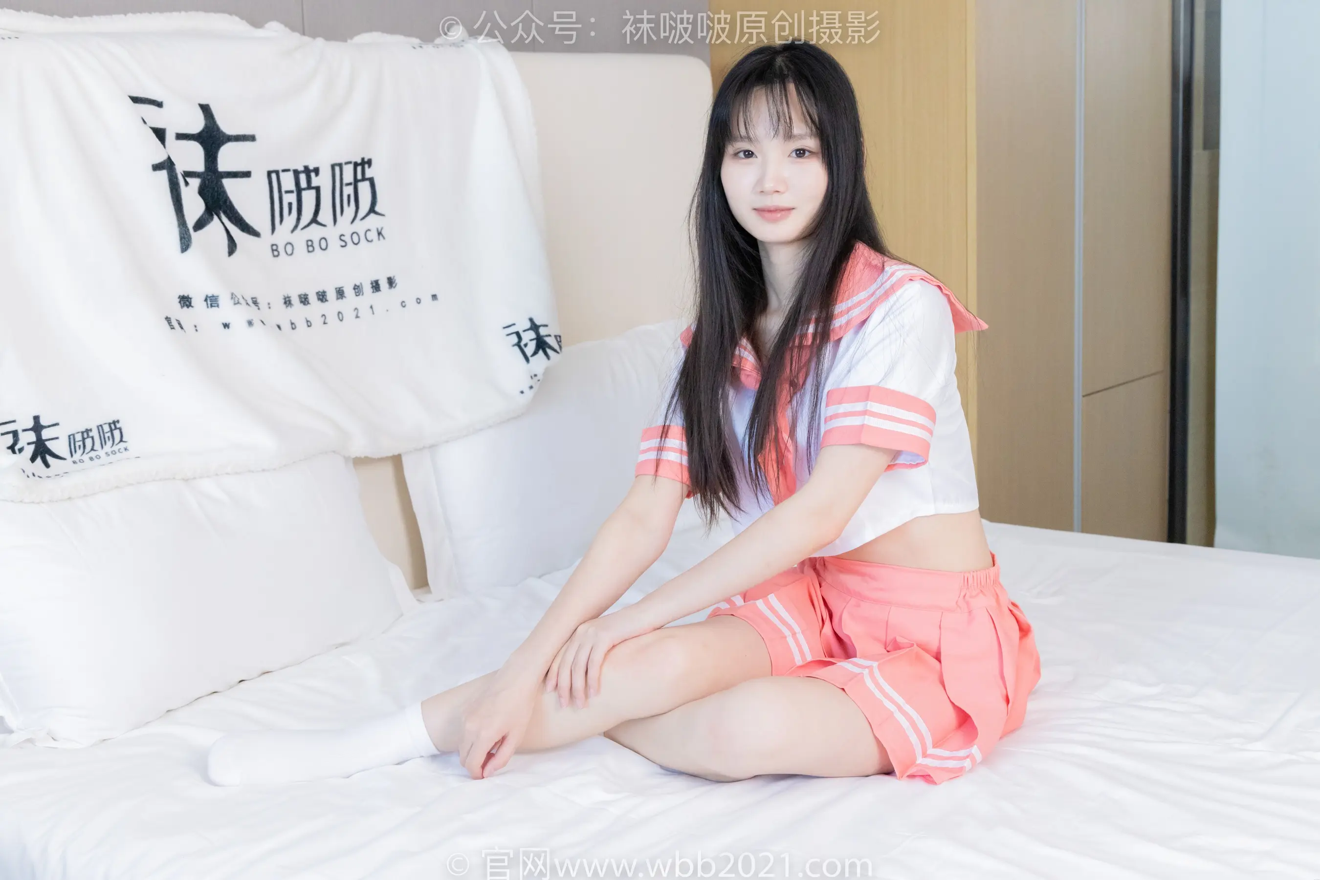 亚洲女人坐在床上，铺着白色床单
