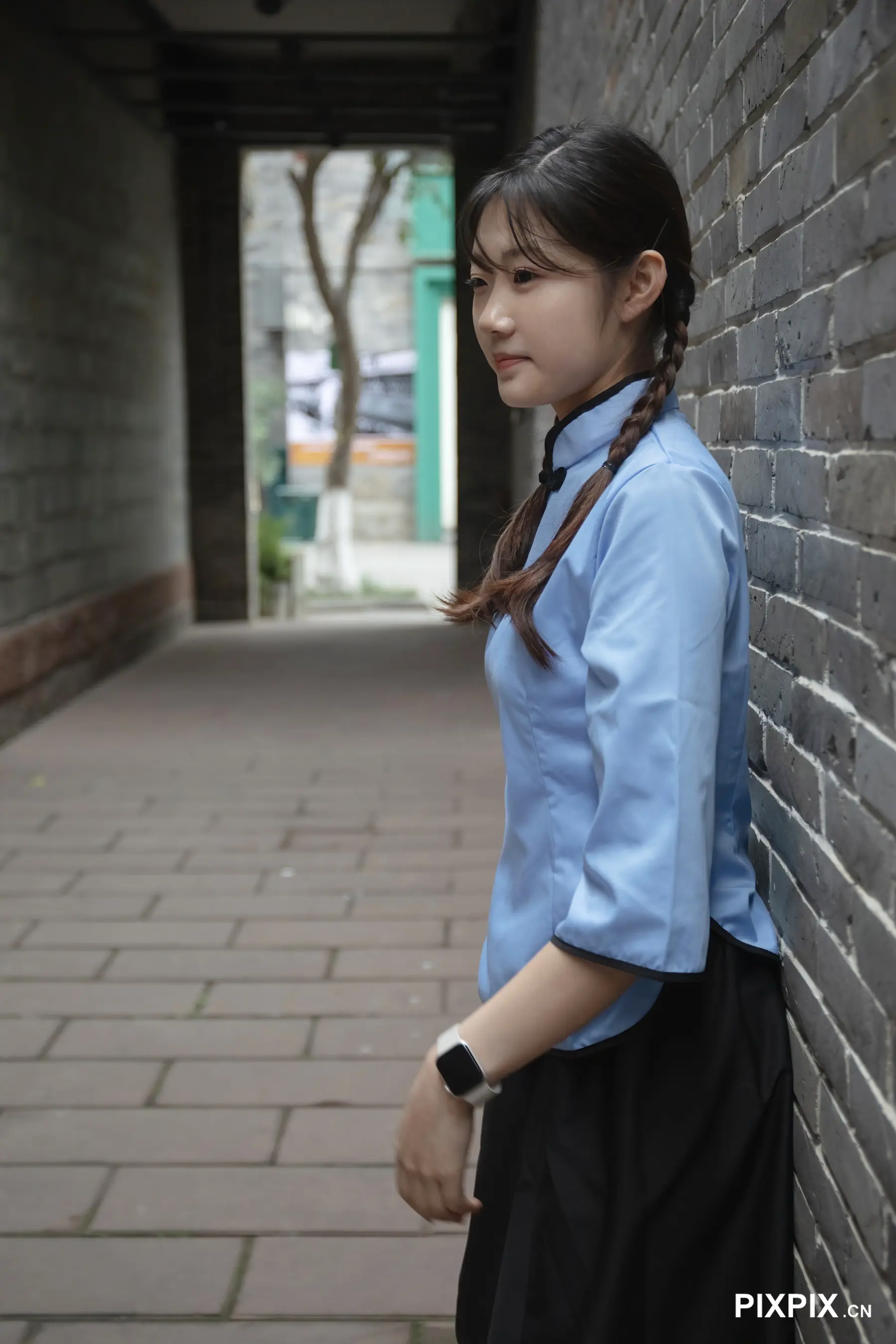 身穿蓝色衬衫站在砖墙上的亚洲女人