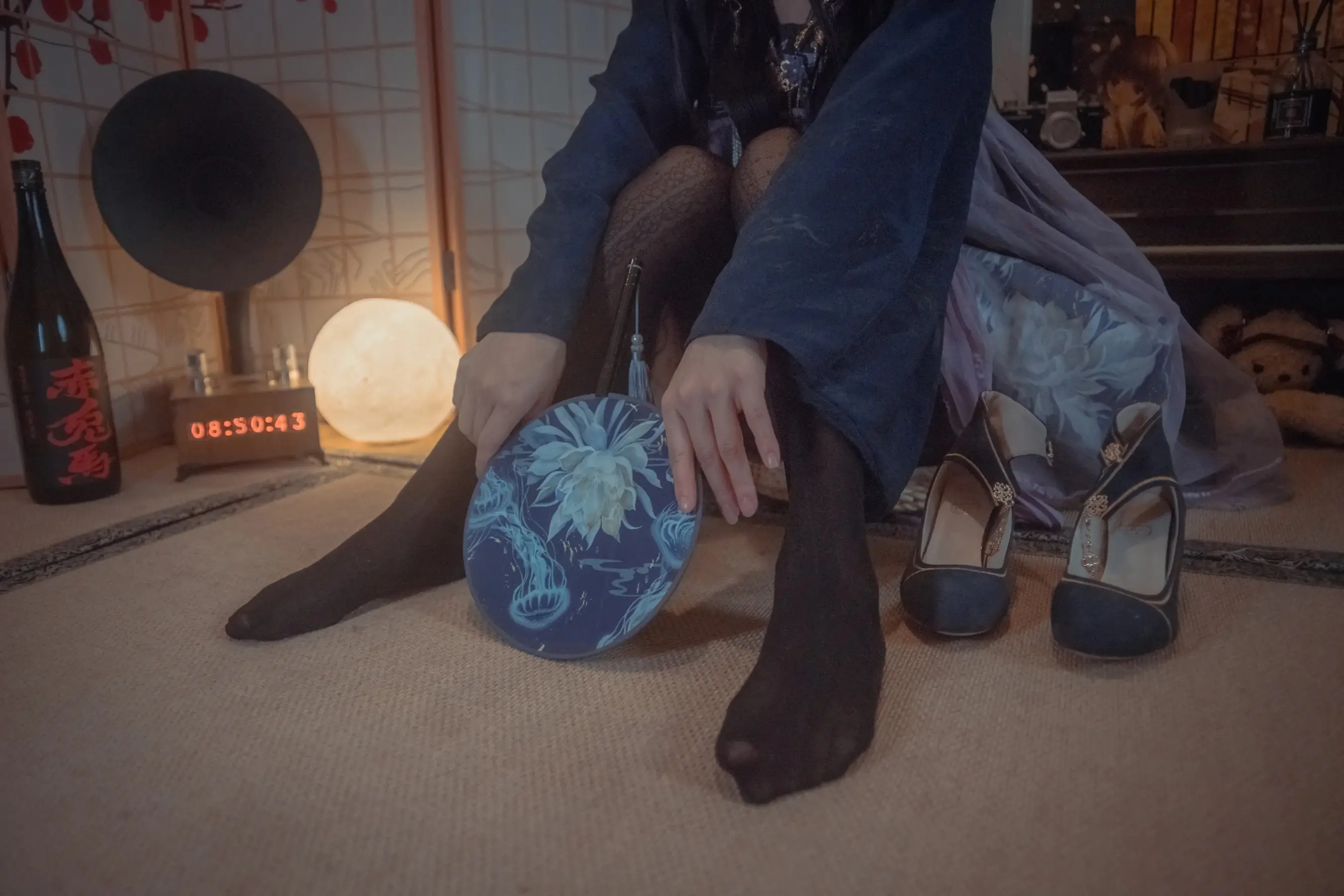有一个女人坐在地板上，拿着钱包和鞋子