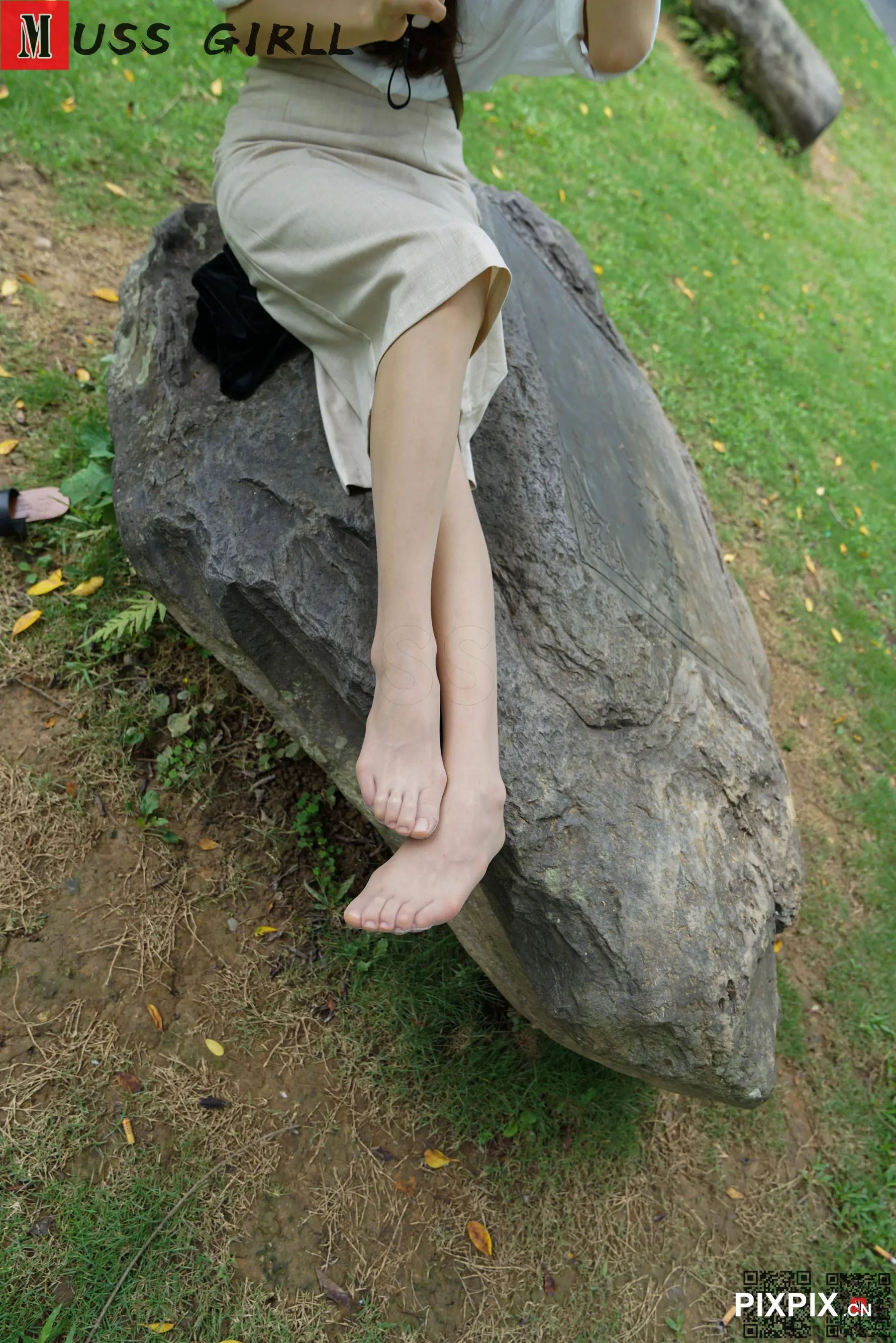 有一个女人撑着伞坐在岩石上